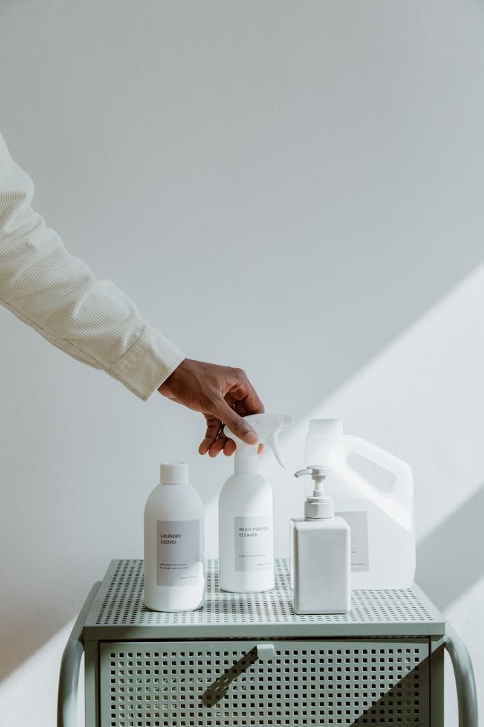A hand reaches for minimalistic cleaning products in bright, airy lighting.